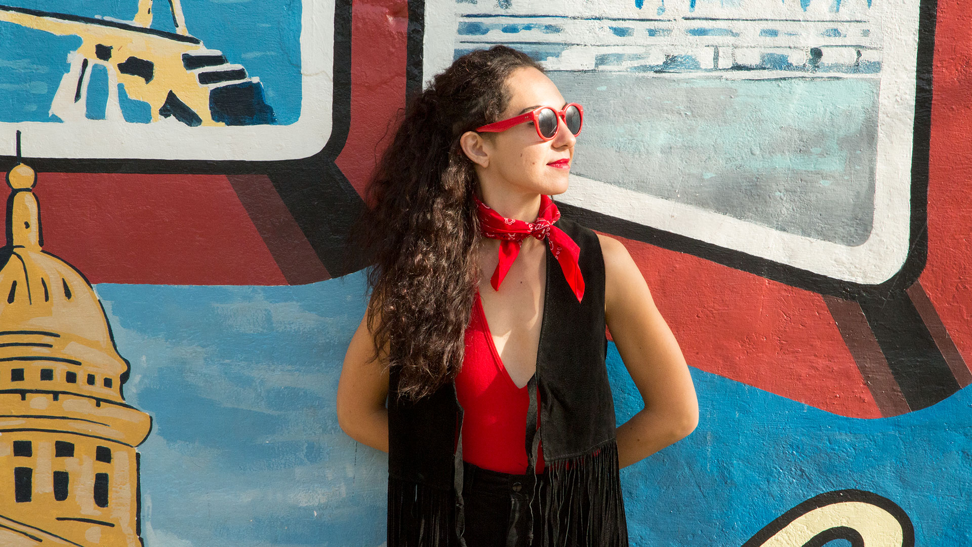 attractive woman stands in front of the iconic Austin postcard mural